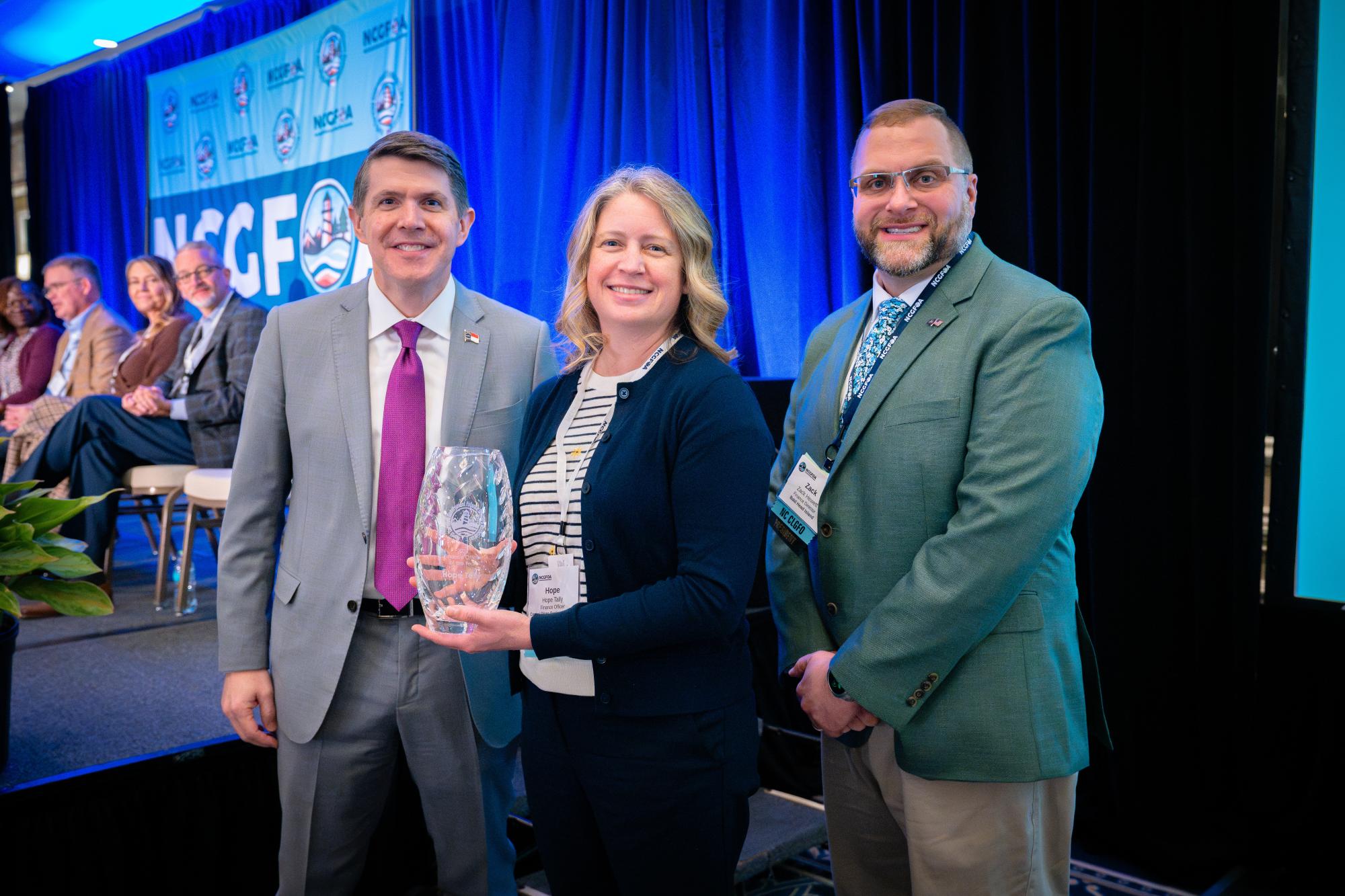 Hope Tally receiving award with State Treasurer and NCGFOA President
