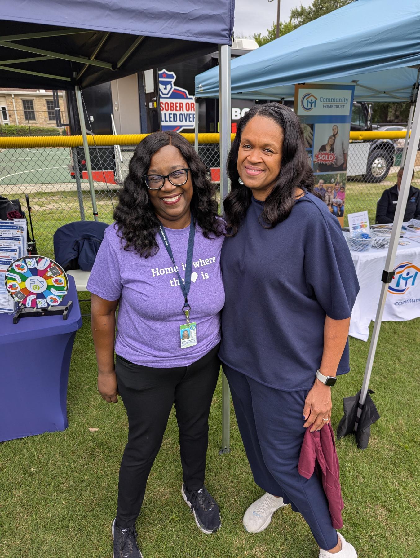 Two women standing and smiling at a community event