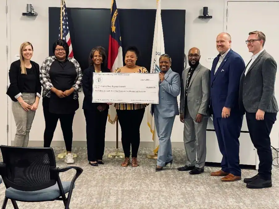 Central Pines Regional Council staff and partners pose with a check for the $1.6 million youth homelessness system improvement grant.