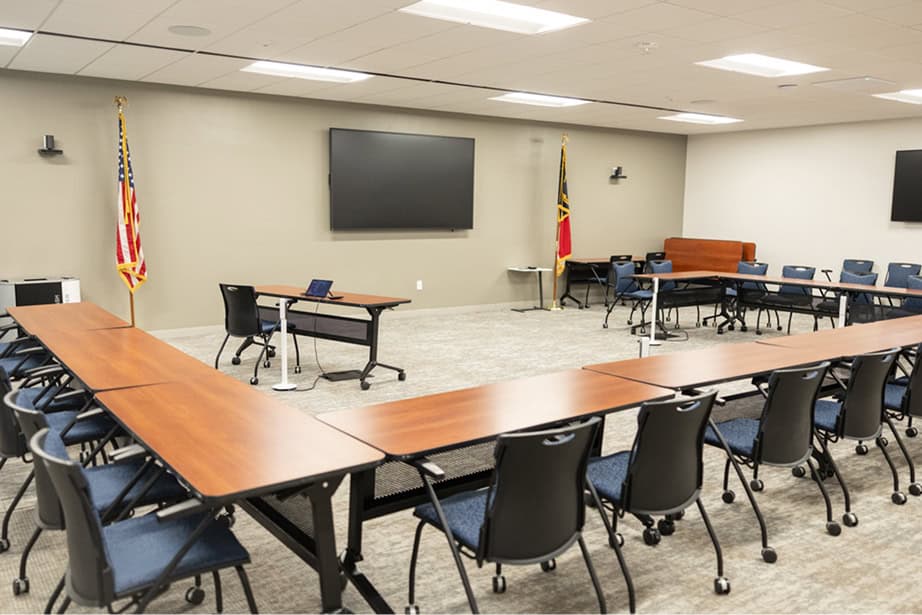 Empty conference room showing u-shaped table arrangement and chairs.