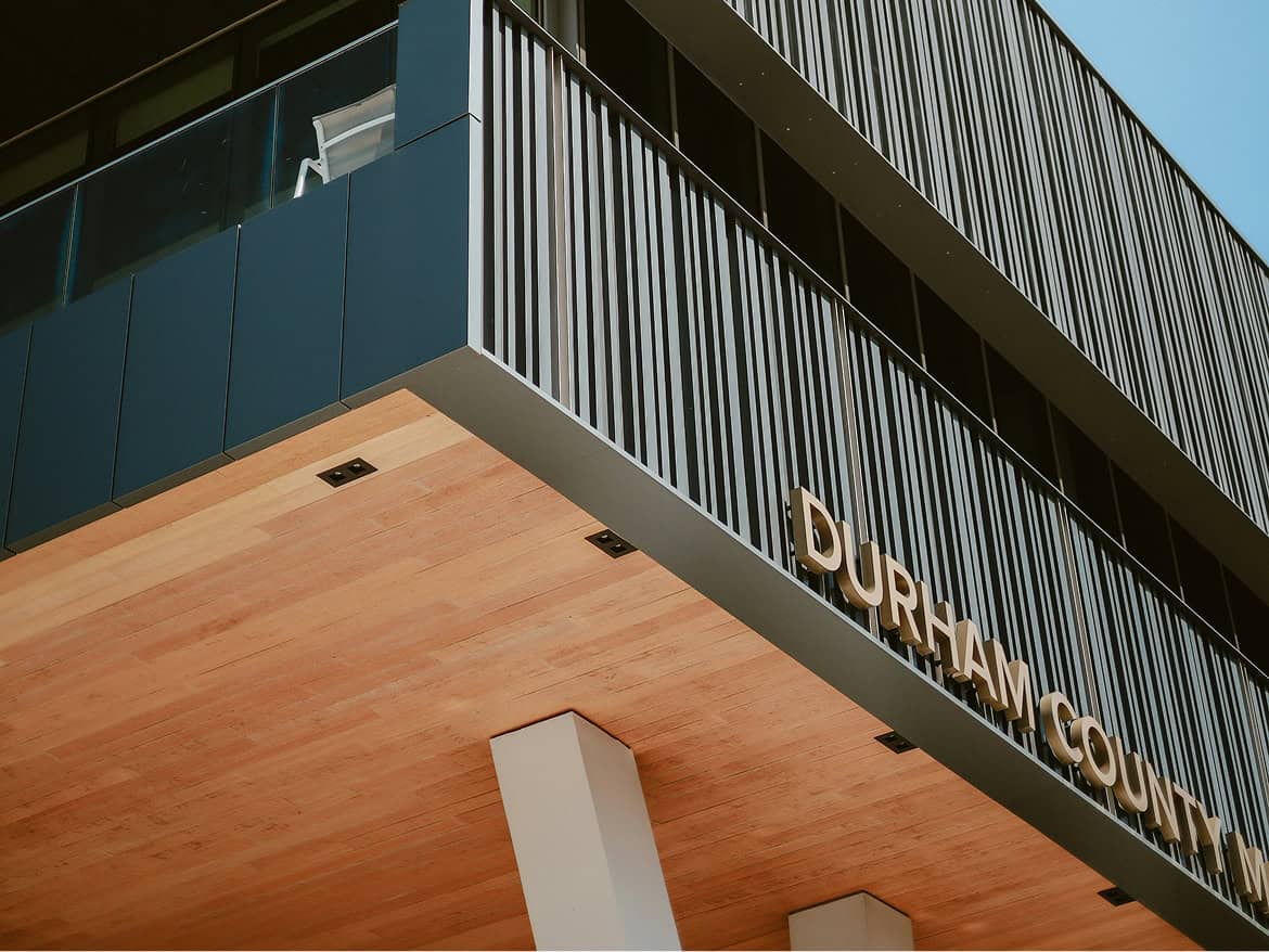Low-angle view of a modern building facade with “Durham County” lettering.