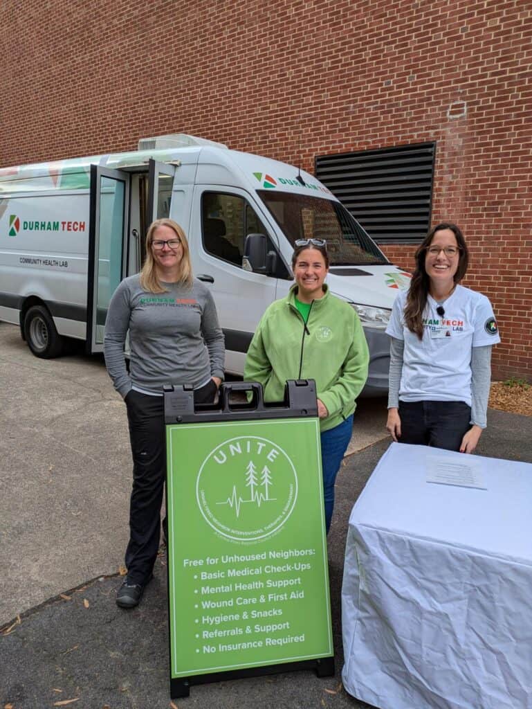 UNITE staff at a table with a van in the background.