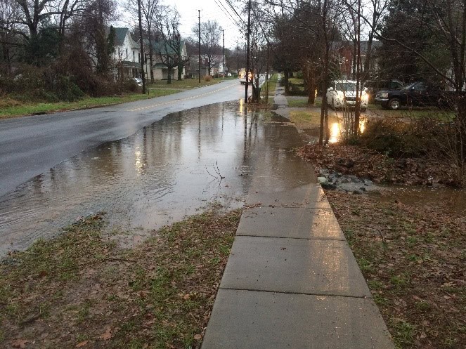 Floodwater covers a sidewalk and pools along a residential street in Siler City.